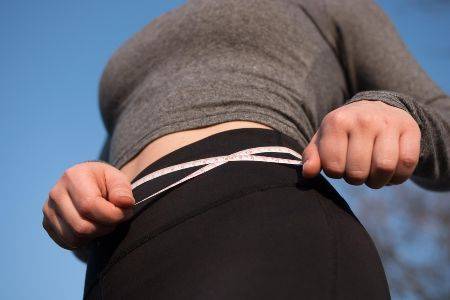 woman with a measuring tape around stomach